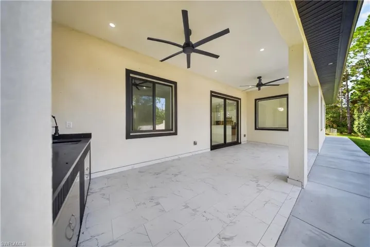 Expansive covered patio featuring two ceiling fans, recessed lighting, and large format tile flooring