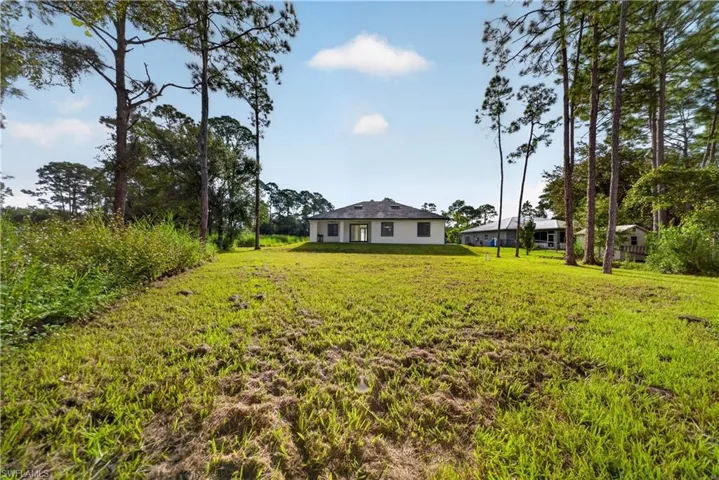 Expansive grounds featuring lush, mature landscaping with towering pine trees framing the property