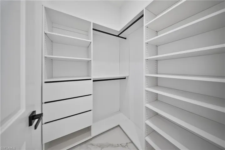Custom closet organization system featuring multiple adjustable shelves, built-in drawers, and black finish hanging rods