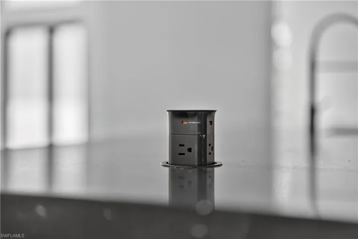 Pop-up electrical outlet with multiple receptacles integrated into a dark countertop