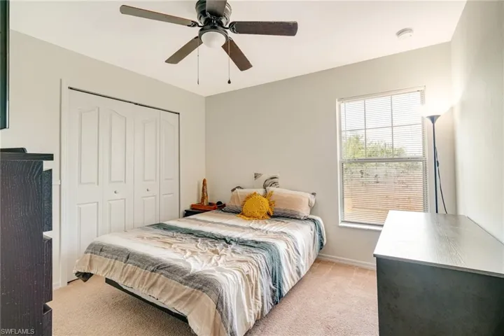 Bedroom featuring a closet, light colored carpet, ceiling fan, and baseboards