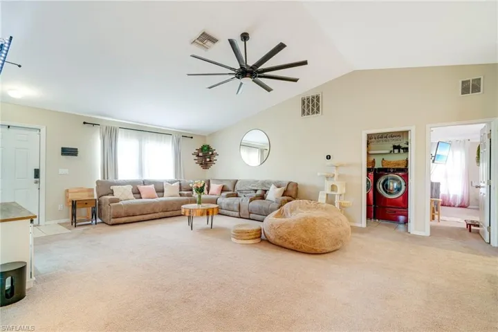 Living room with light carpet, washer and clothes dryer, and visible vents