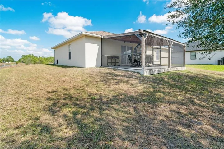 Back of house featuring a yard, a patio area, and stucco siding