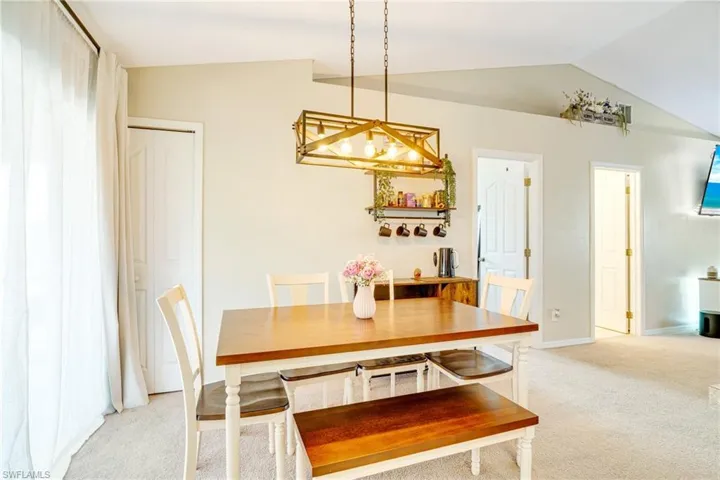 Dining space with light colored carpet, vaulted ceiling, and baseboards