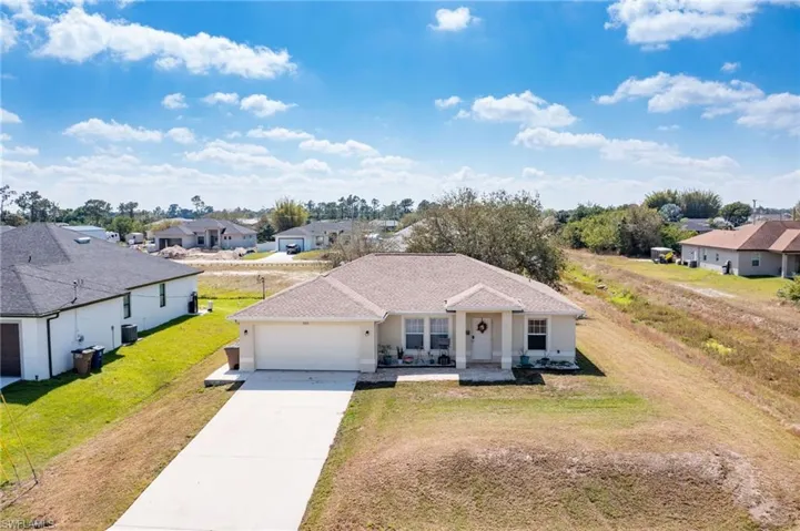 View of front of house with an attached garage, a shingled roof, concrete driveway, a residential view, and a front yard