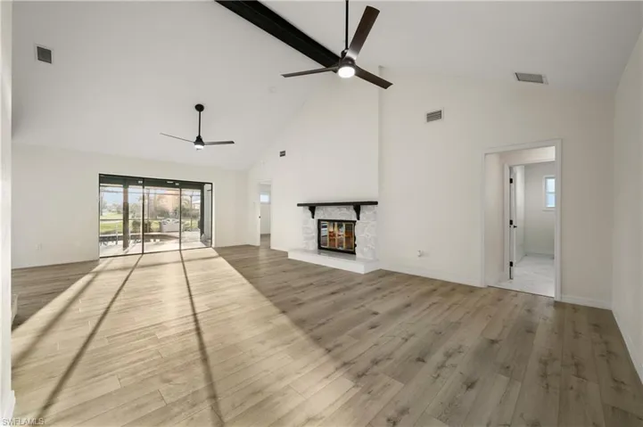 Unfurnished living room with high vaulted ceiling, a fireplace, light wood-type flooring, and ceiling fan