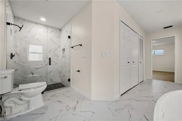 Bathroom with tile patterned flooring, a shower with shower door, and toilet