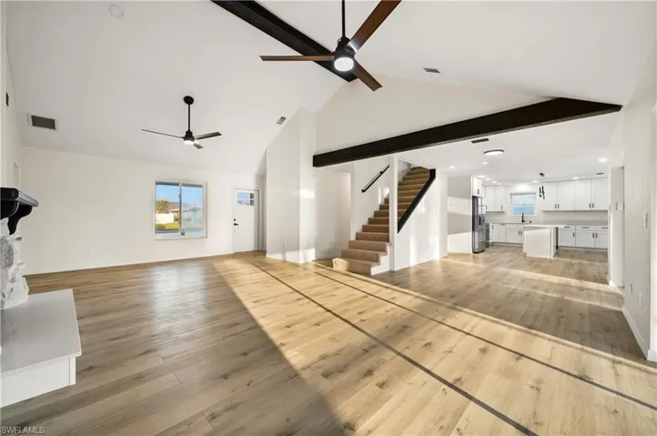 Unfurnished living room with light hardwood / wood-style floors, high vaulted ceiling, and ceiling fan