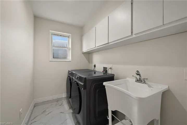 Washroom with sink, cabinets, washer and clothes dryer, and light tile patterned floors