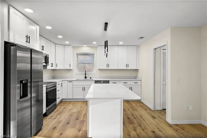 Kitchen with sink, white cabinetry, light wood-type flooring, and stainless steel appliances
