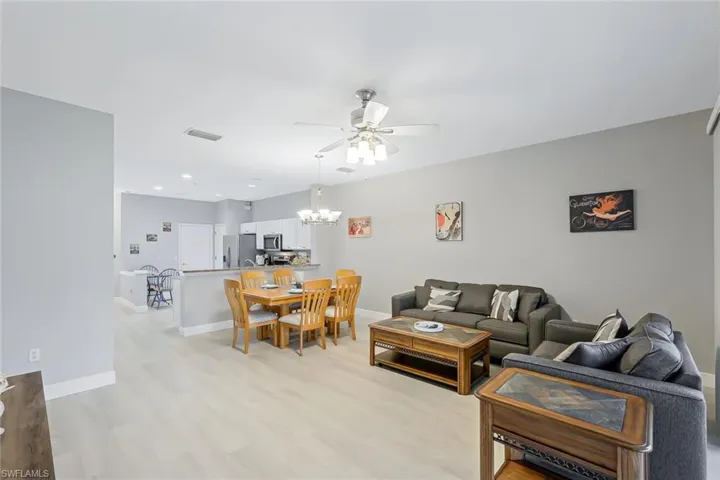 Living room featuring light wood-type flooring and ceiling fan with notable chandelier