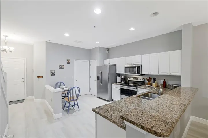 Kitchen with light wood-type flooring, appliances with stainless steel finishes, kitchen peninsula, pendant lighting, and sink