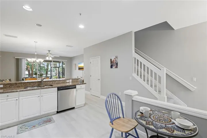 Kitchen with dark stone counters, stainless steel dishwasher, light wood-type flooring, sink, and white cabinetry