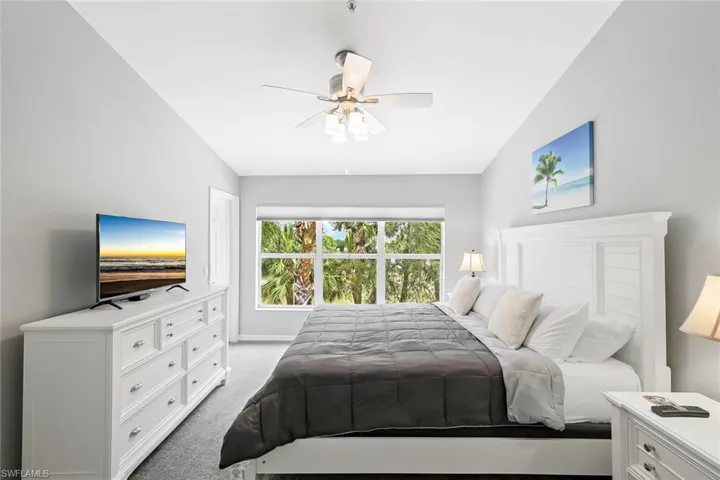 Carpeted bedroom featuring lofted ceiling and ceiling fan