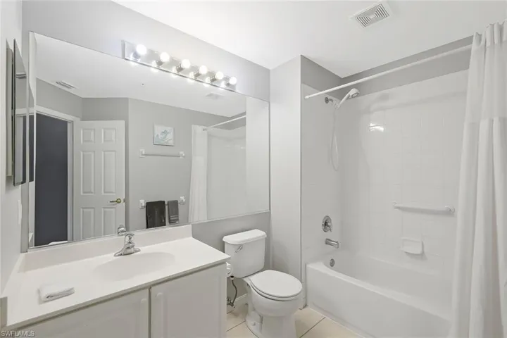 Full bathroom with tile floors, shower / bath combination with curtain, vanity, and toilet