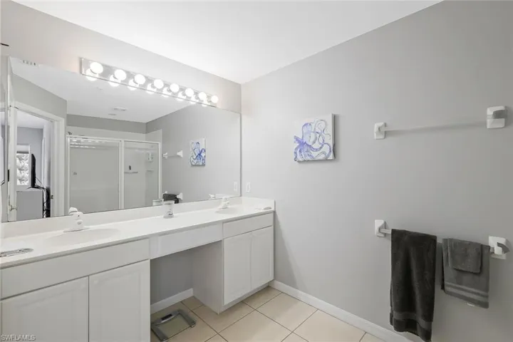 Bathroom with an enclosed shower, tile flooring, vanity with extensive cabinet space, and dual sinks