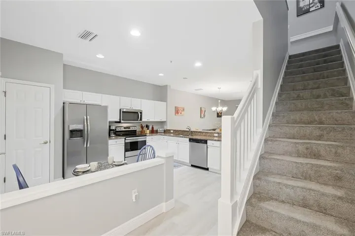Kitchen featuring white cabinetry, light hardwood / wood-style floors, pendant lighting, and stainless steel appliances