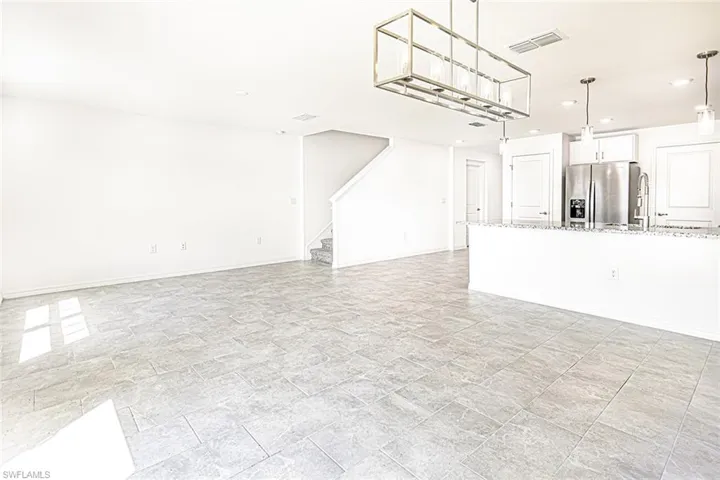 Unfurnished living room with stone finish flooring, stairs, visible vents, and recessed lighting