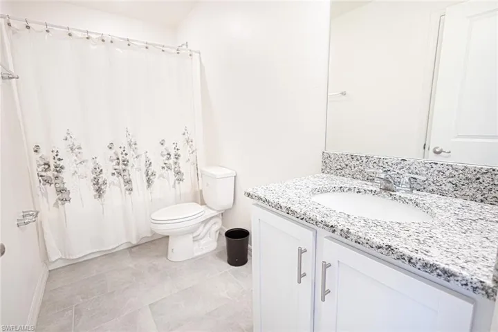 Full bathroom featuring a shower with shower curtain, vanity, baseboards, and toilet