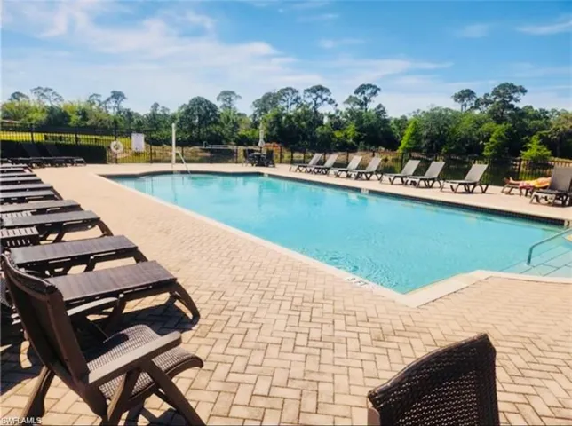 Community pool with a patio area and fence