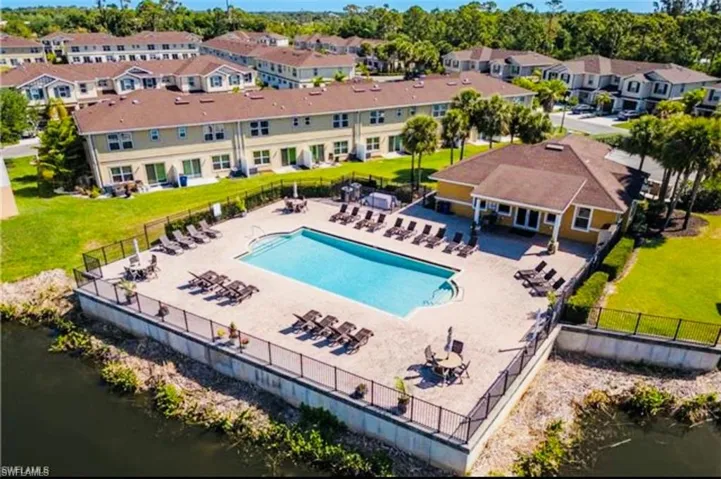 Community pool featuring a yard, a water view, fence, and a residential view