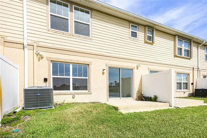 Back of house featuring a patio, fence, central AC unit, and a lawn