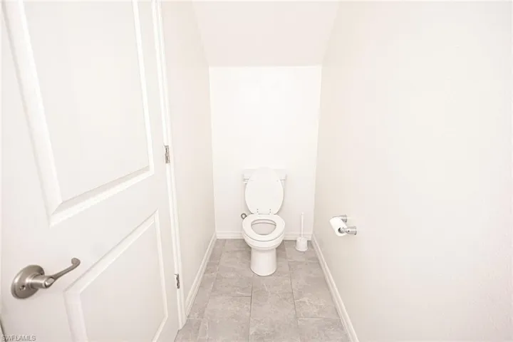 Bathroom with toilet, tile patterned flooring, and baseboards