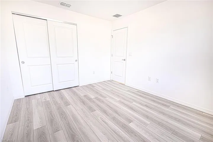 Unfurnished bedroom featuring light wood-style flooring, baseboards, and visible vents