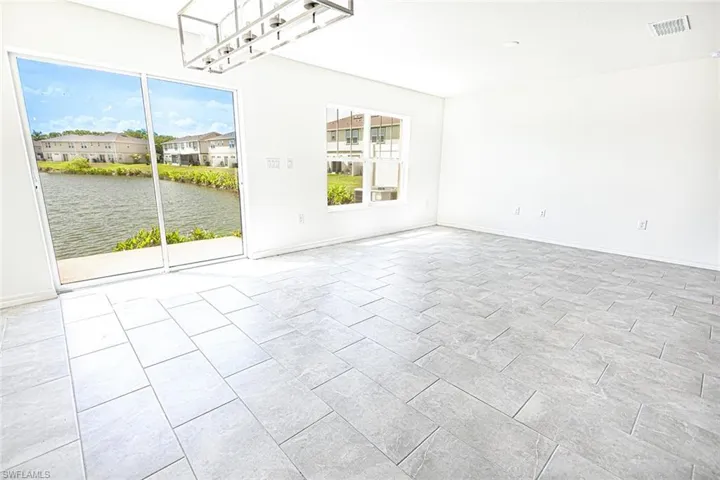 Empty room with baseboards, visible vents, and a water view