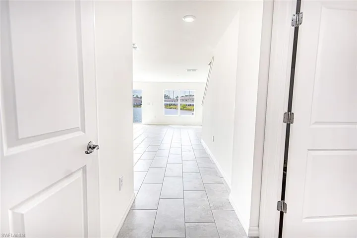 Corridor with a water view, light tile patterned floors, baseboards, and visible vents