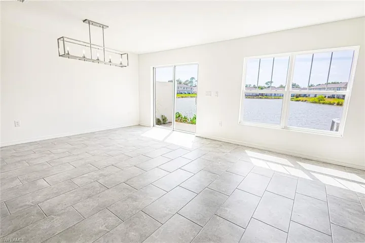 Empty room featuring a chandelier, light tile patterned floors, a water view, and baseboards