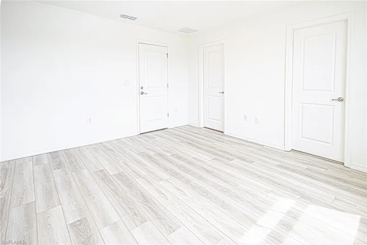 Empty room featuring light wood-type flooring, baseboards, and visible vents