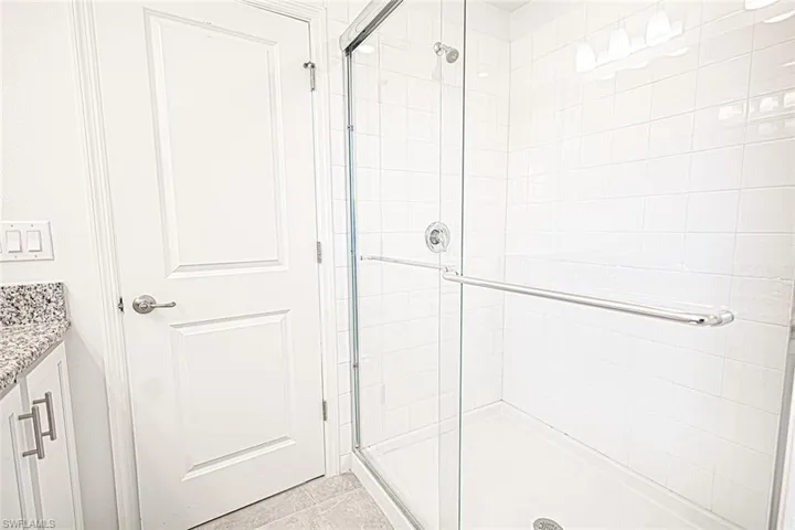 Bathroom with tile patterned flooring, a shower stall, and vanity