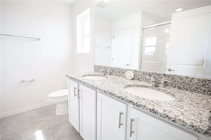 Bathroom featuring a shower stall, baseboards, a sink, and toilet