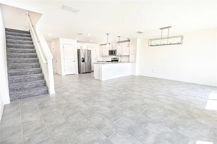 Unfurnished living room with visible vents, baseboards, stairway, and recessed lighting