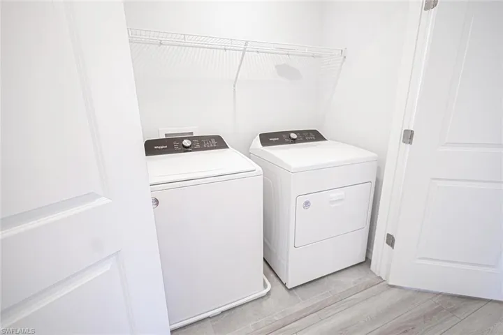 Clothes washing area featuring washer and clothes dryer, light wood-style floors, and laundry area