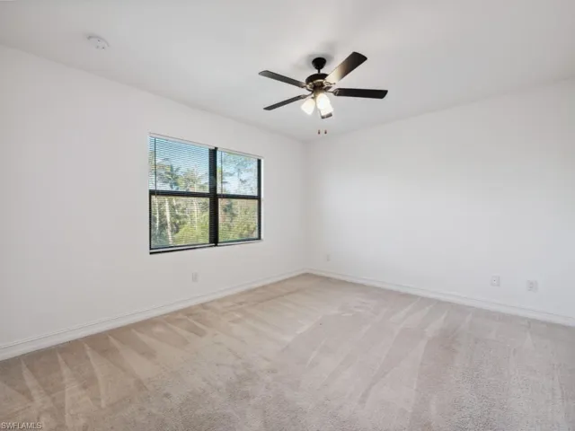Carpeted empty room featuring ceiling fan