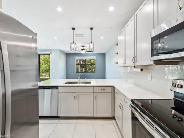 Kitchen featuring pendant lighting, sink, light tile patterned floors, stainless steel appliances, and kitchen peninsula