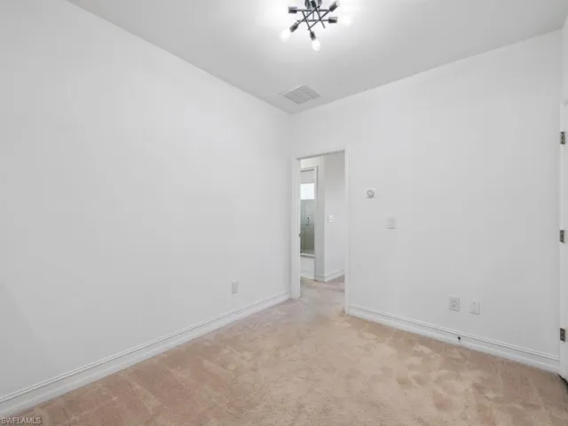 Carpeted empty room with an inviting chandelier