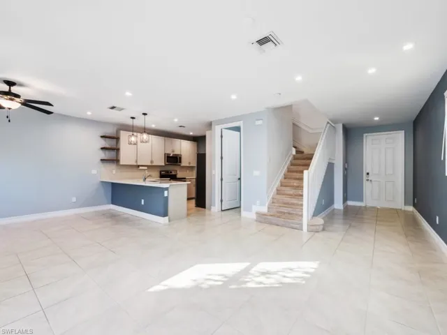 Kitchen with a kitchen bar, decorative light fixtures, kitchen peninsula, stainless steel appliances, and decorative backsplash