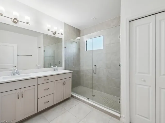 Bathroom featuring tile patterned flooring, vanity, and a shower with shower door