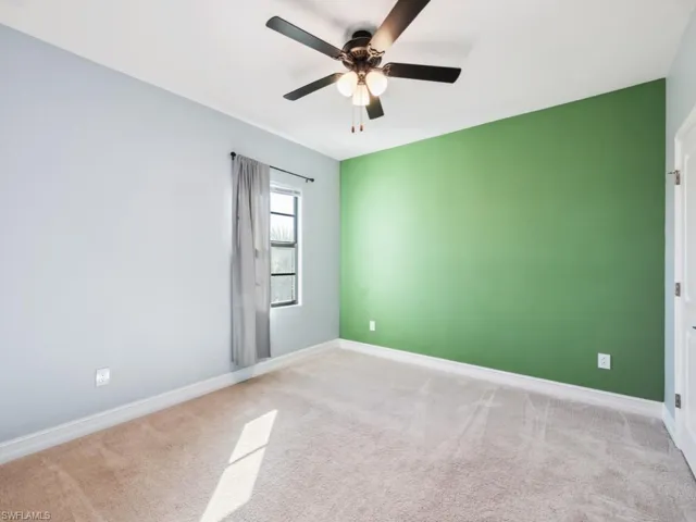 Carpeted spare room featuring ceiling fan