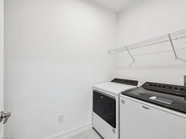 Laundry room featuring light tile patterned floors and washer and clothes dryer