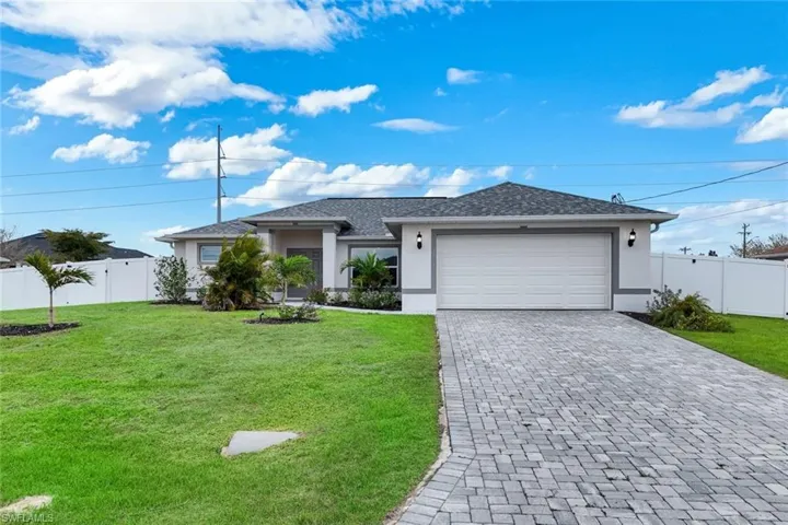 View of front of home with an attached garage, stucco siding, decorative driveway, and a gate