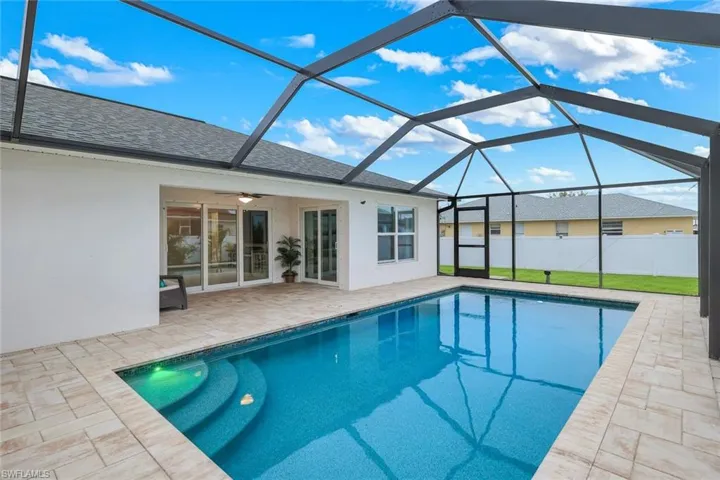 View of swimming pool with a sunroom, patio surround, and glass enclosure