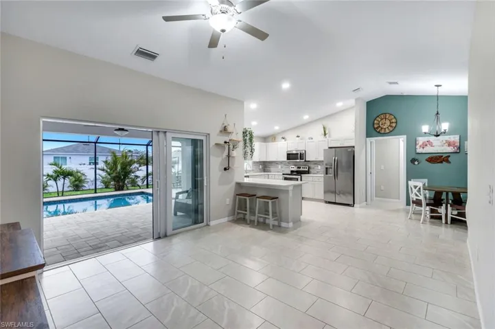 Kitchen featuring a peninsula, a kitchen bar, white cabinetry, a ceiling fan, and stainless steel appliances