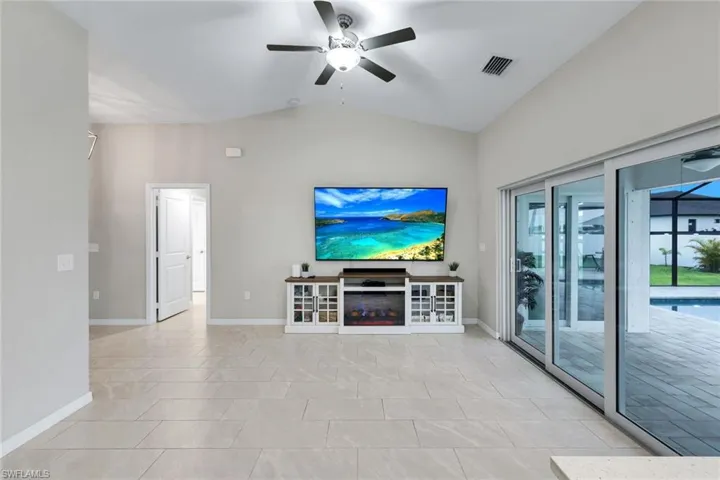 Unfurnished living room with a ceiling fan, vaulted ceiling, and light tile patterned floors