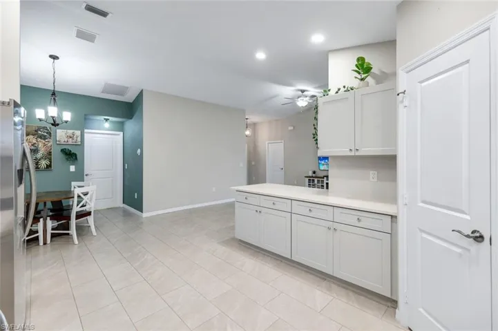 Kitchen featuring light countertops, stainless steel fridge with ice dispenser, ceiling fan, suspended lighting, and light tile patterned floors