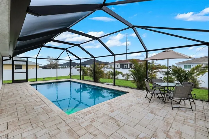 View of pool featuring a sunroom, a lanai, patio surround, and outdoor dining space