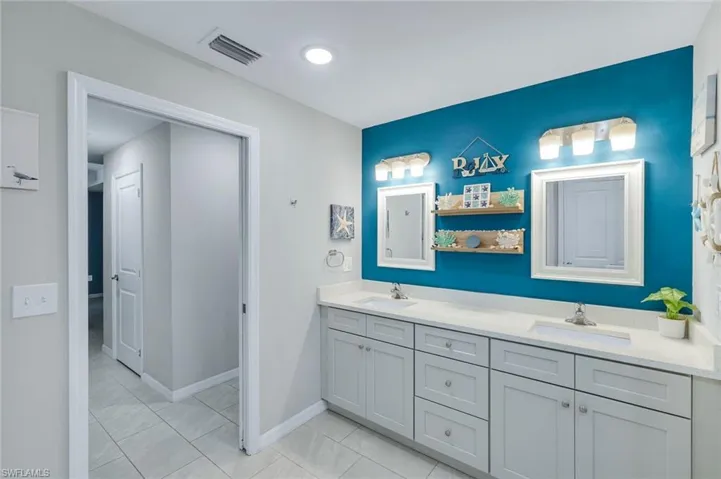 Bathroom with double vanity and light tile patterned floors